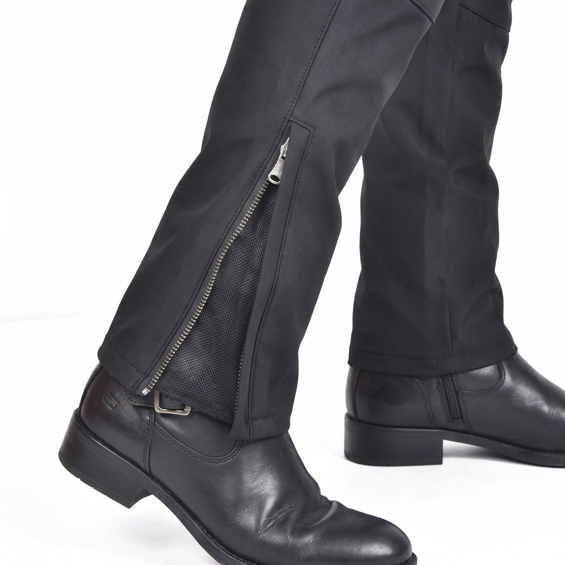 Black riding pants with the ankle zip open over a black leather boot, mesh gusset showing behind the zip